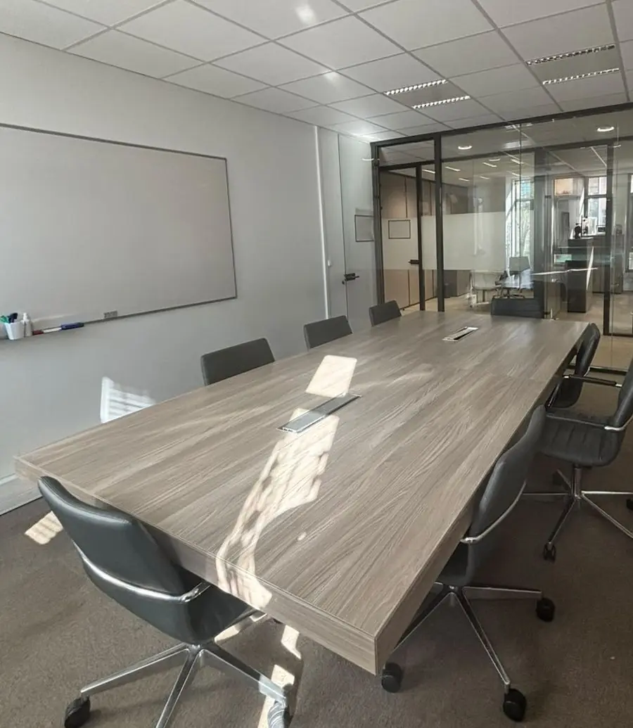 Salle de réunion avec grande table et tableau blanc